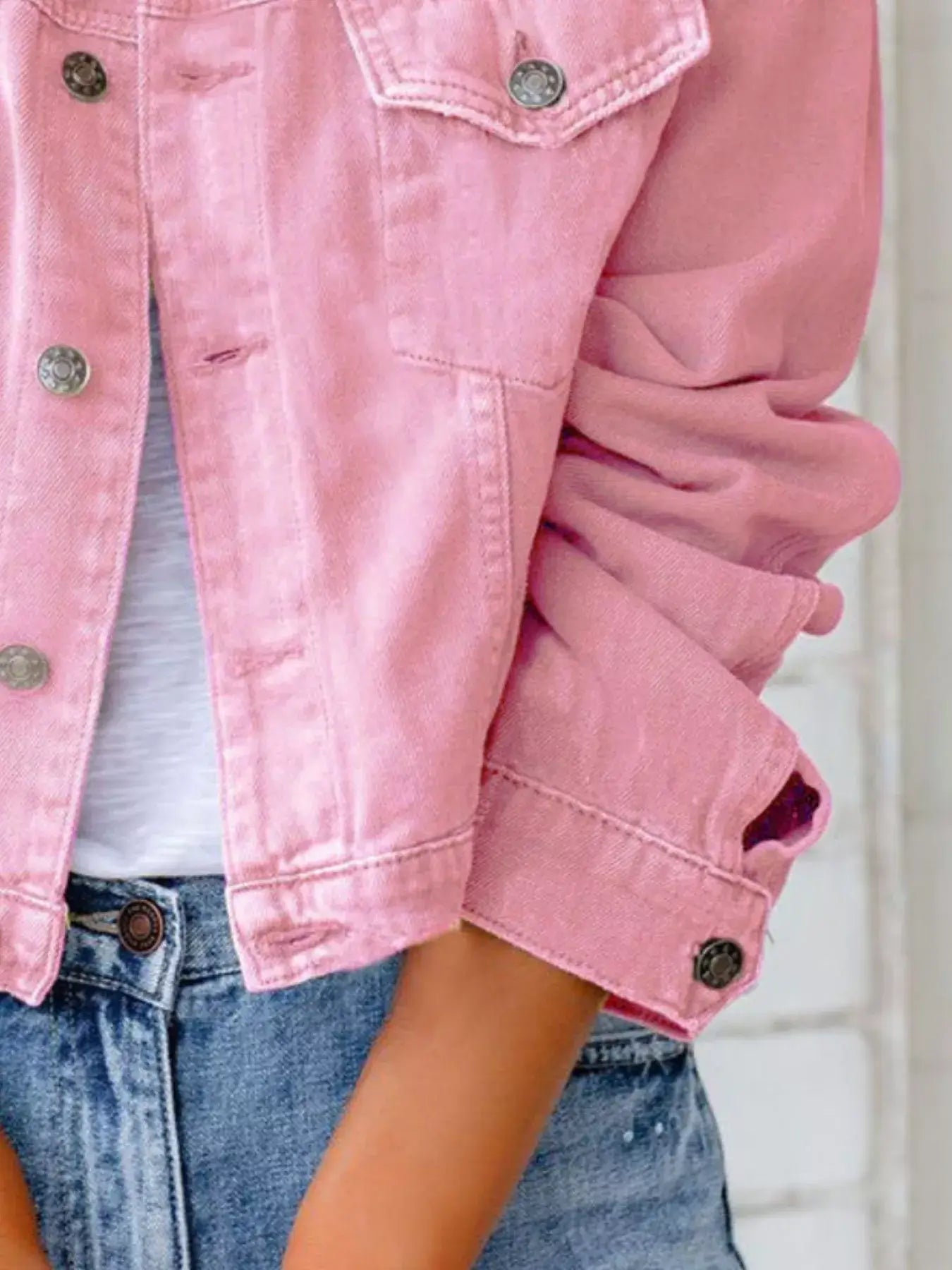 Close-up of a pink button-up denim jacket for women, featuring long sleeves and stylish design.