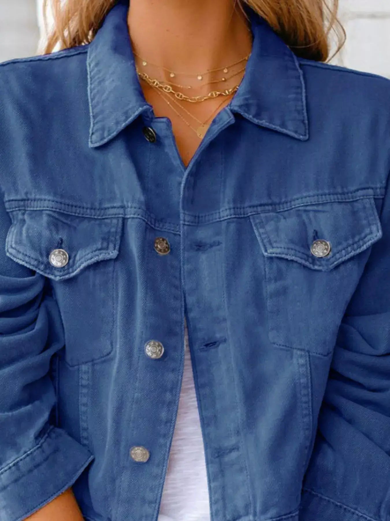Close-up of a women's button-up long sleeve denim jacket, featuring button-front closure and classic design.
