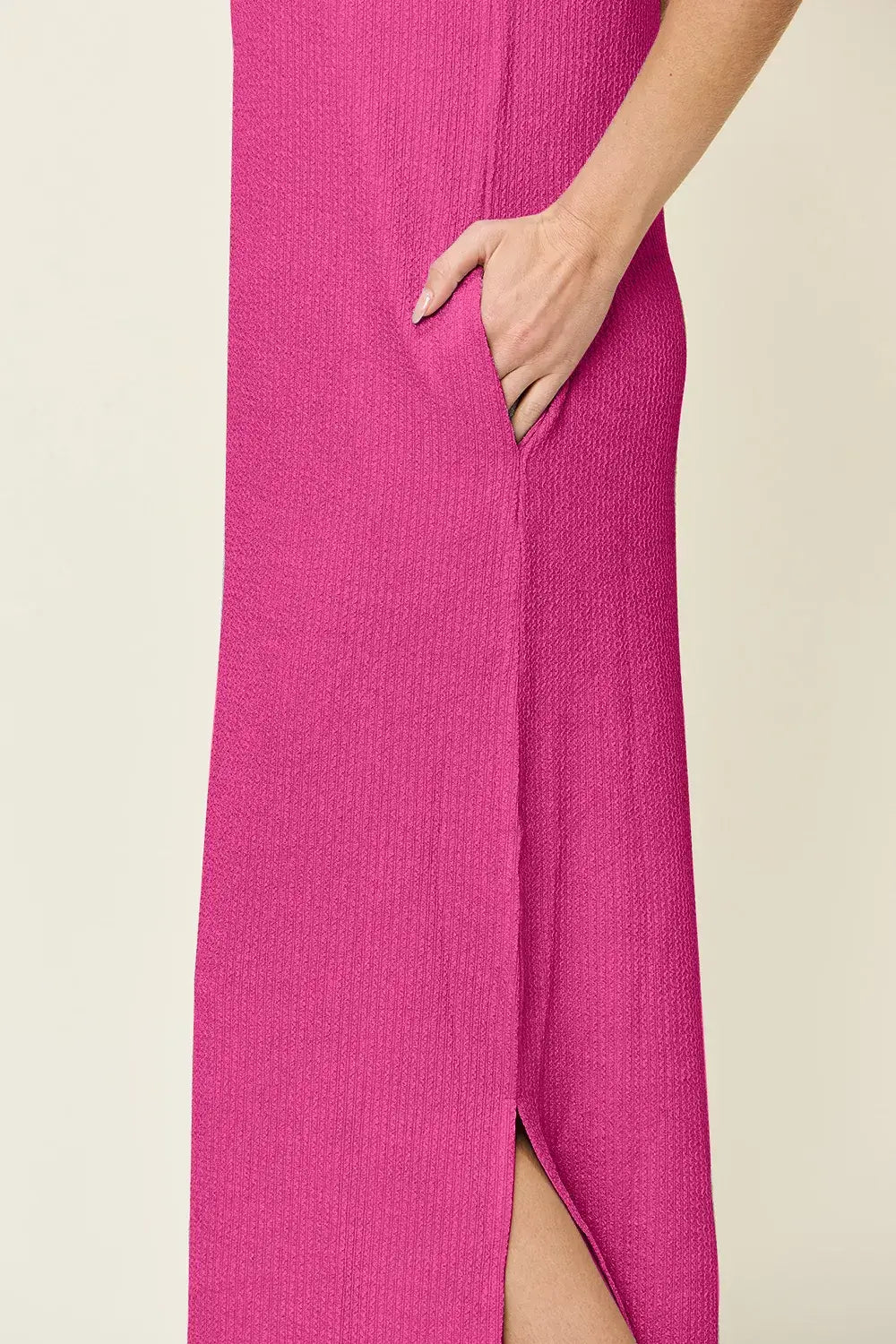Side view of a pink sleeveless maxi dress showcasing a side slit and textured fabric.