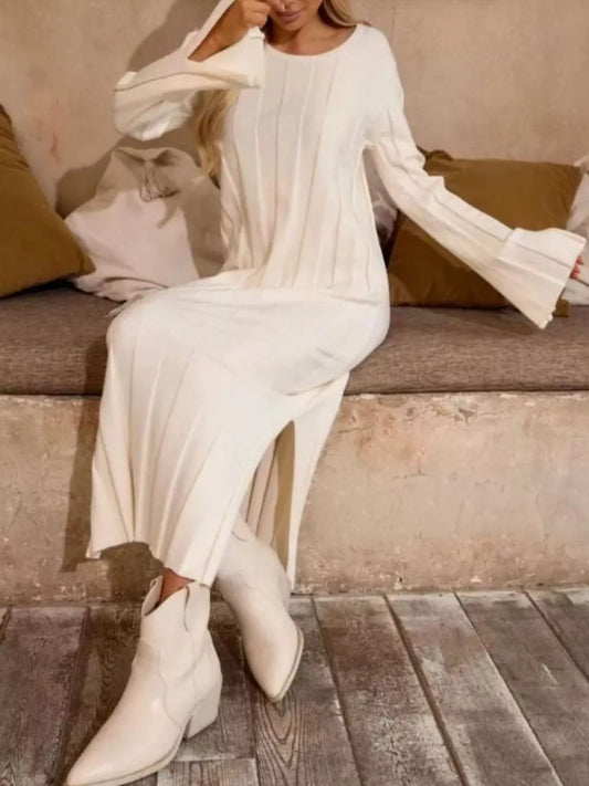 Model wearing a white Ribbed Knit Slit Sweater Dress with bell sleeves, sitting on a couch.