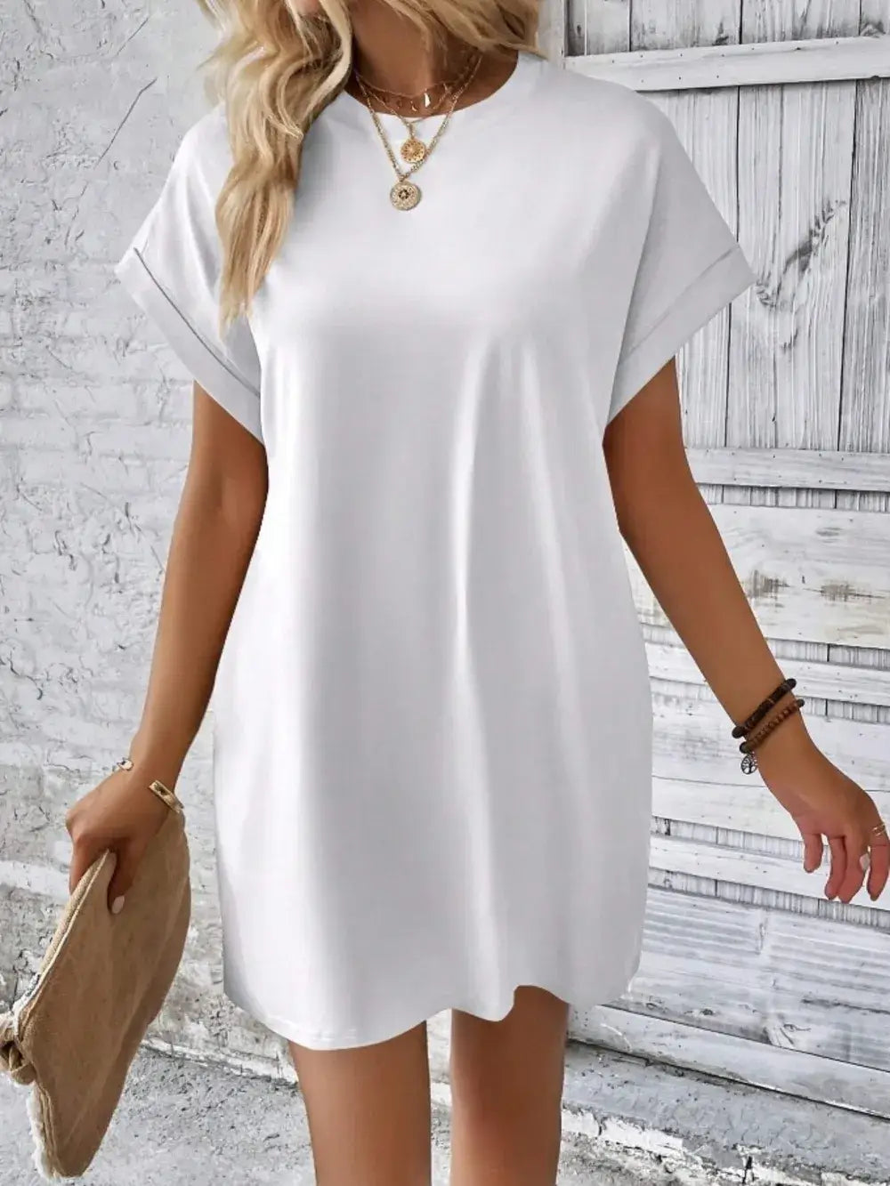 Model wearing a white pocketed round neck short sleeve dress, paired with accessories and holding a clutch bag.