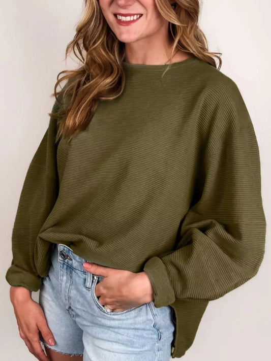 Woman wearing a Ribbed Knit Oversized Sweatshirt in olive green with a relaxed fit over denim shorts.