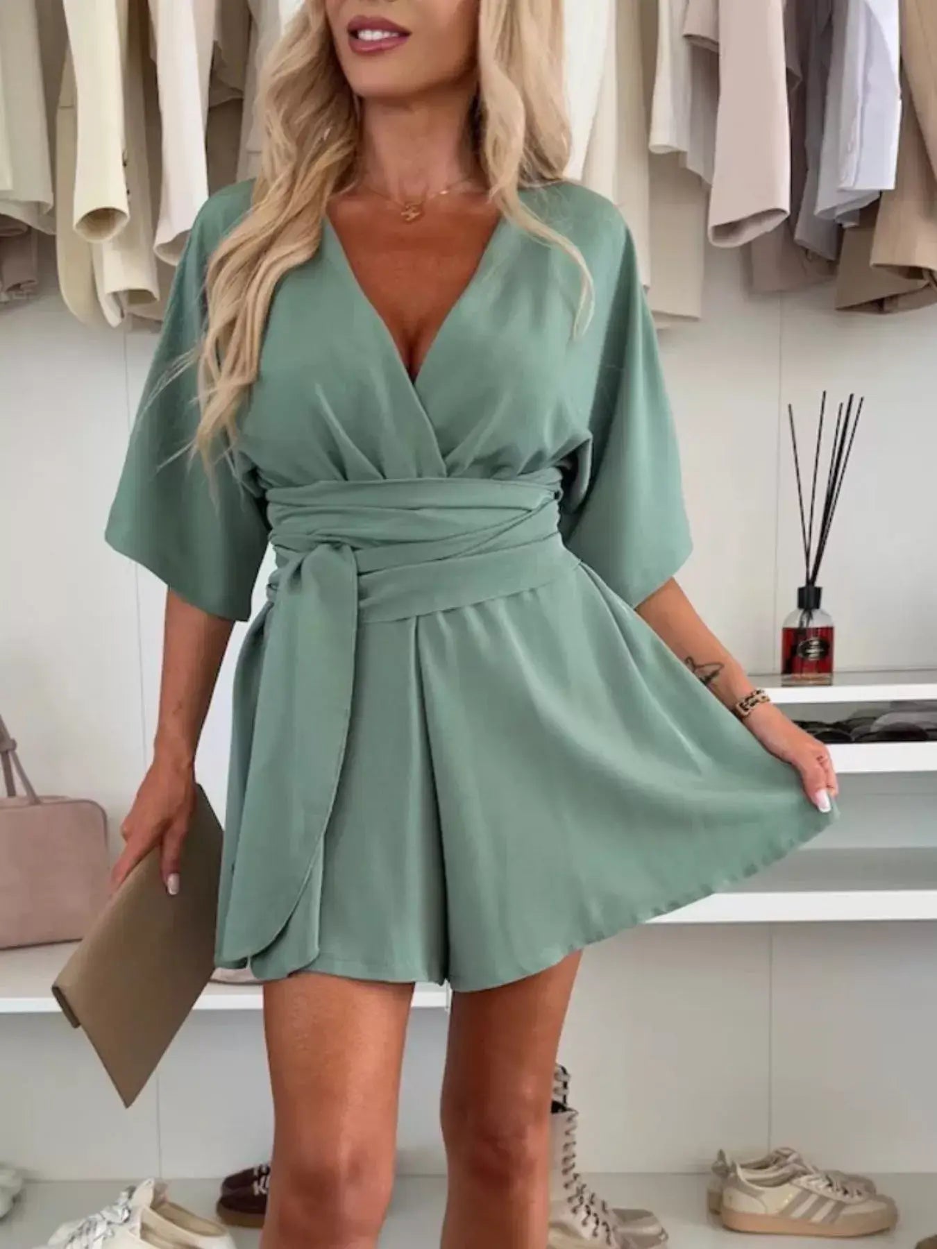 Full Size Surplice Tie Waist Romper in green displayed by a model, showcasing the elegant neckline and tie waist detail.