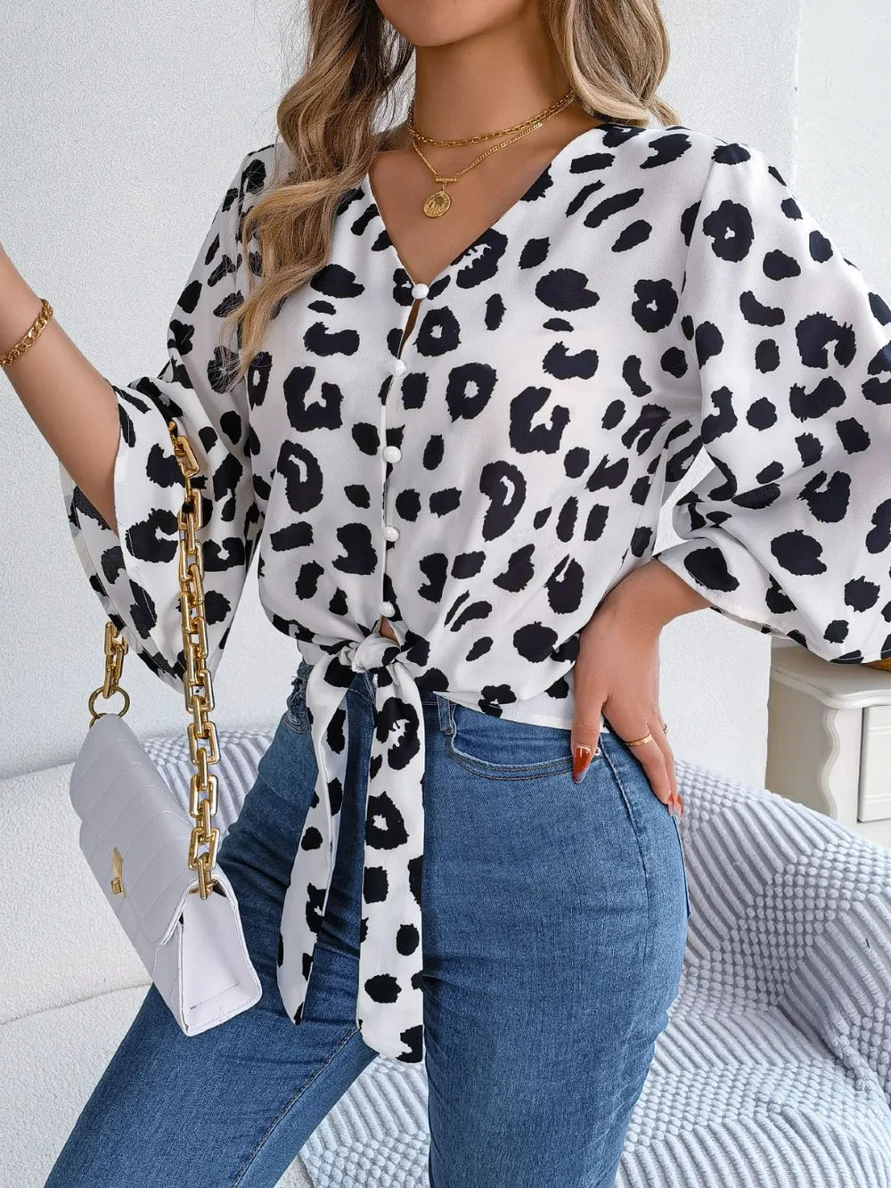 Tied Button Up Leopard V-Neck Blouse styled with jeans and a handbag, featuring a tied front design and leopard print.