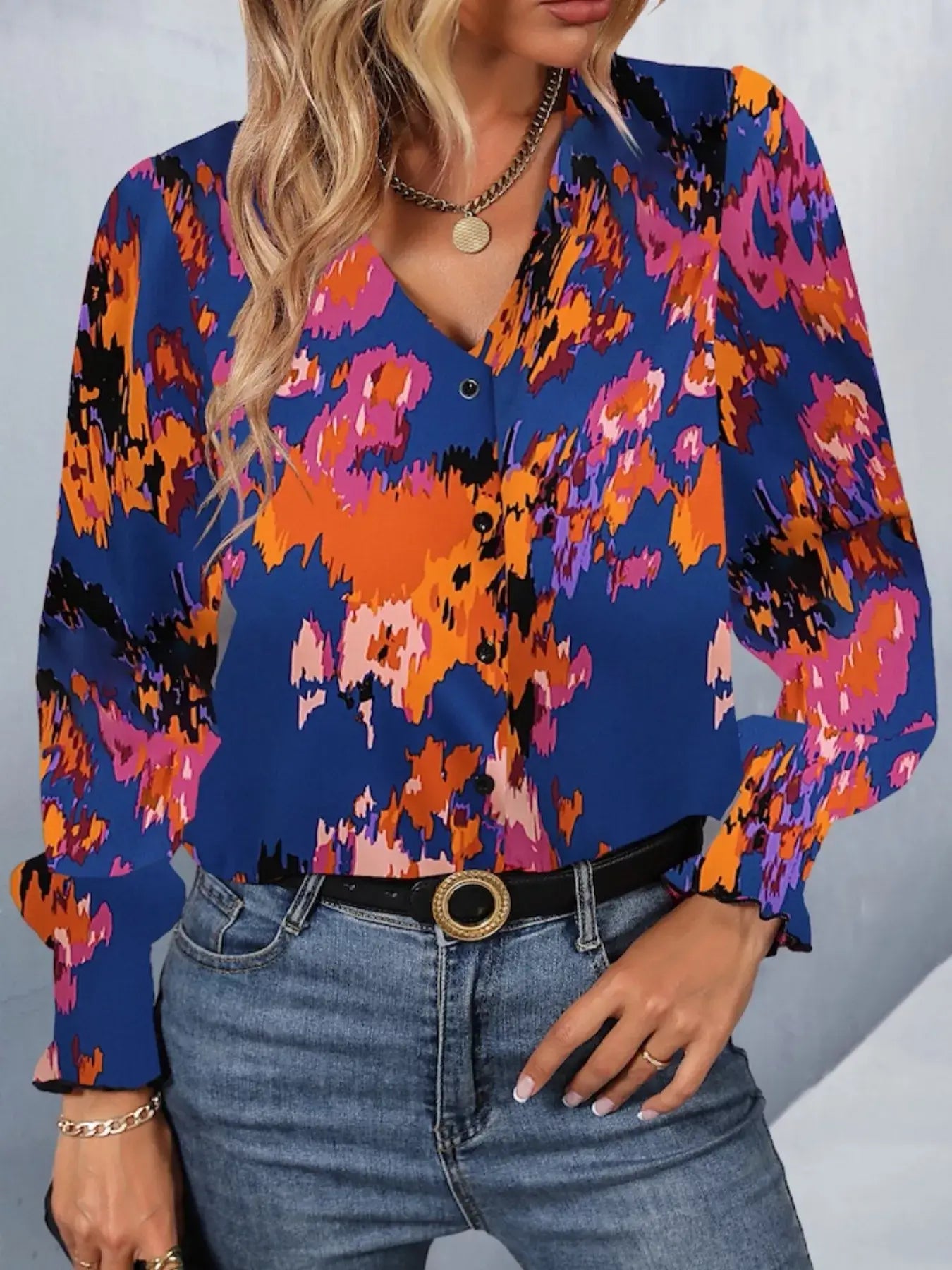 Printed button up long sleeve shirt in vibrant floral pattern, styled with jeans for a chic look.