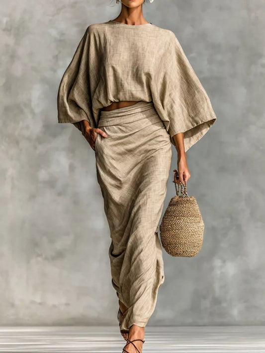 Model wearing Kimono Sleeve Top and Ruched Skirt Set in a neutral color, styled with a woven bag.