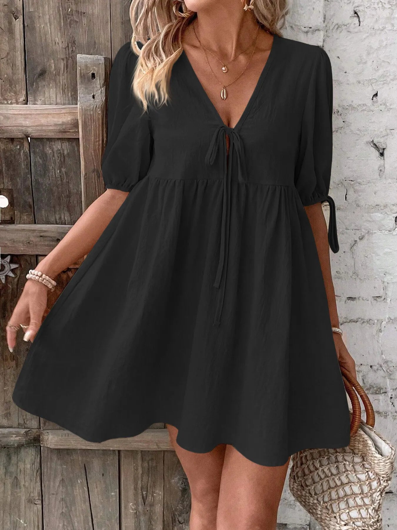 V-Neck Tie-Front Mini Dress with Puff Sleeves displayed on a model in a black color against a wooden background.