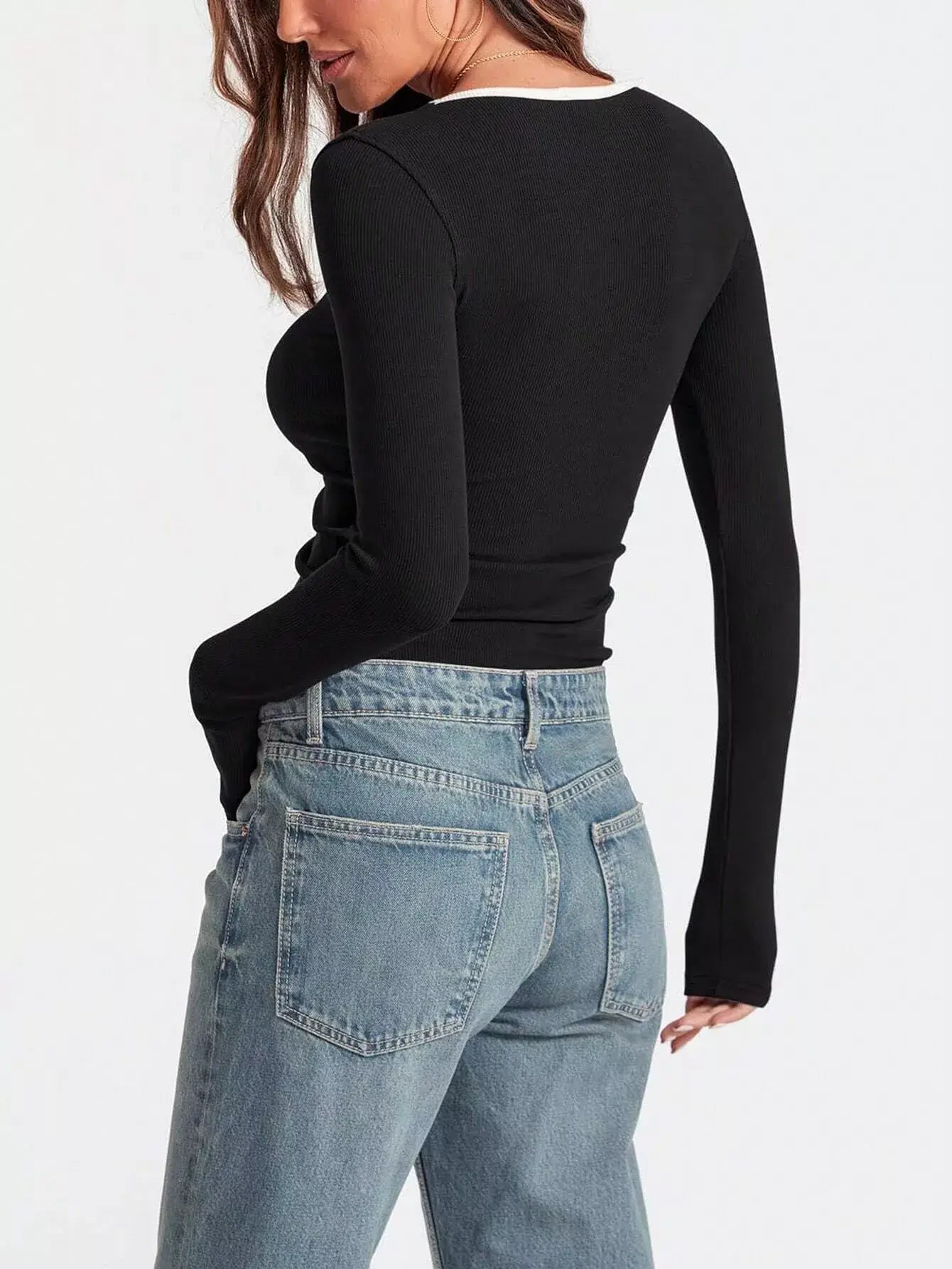 Back view of a woman wearing a black scoop neck long sleeve t-shirt with denim jeans.