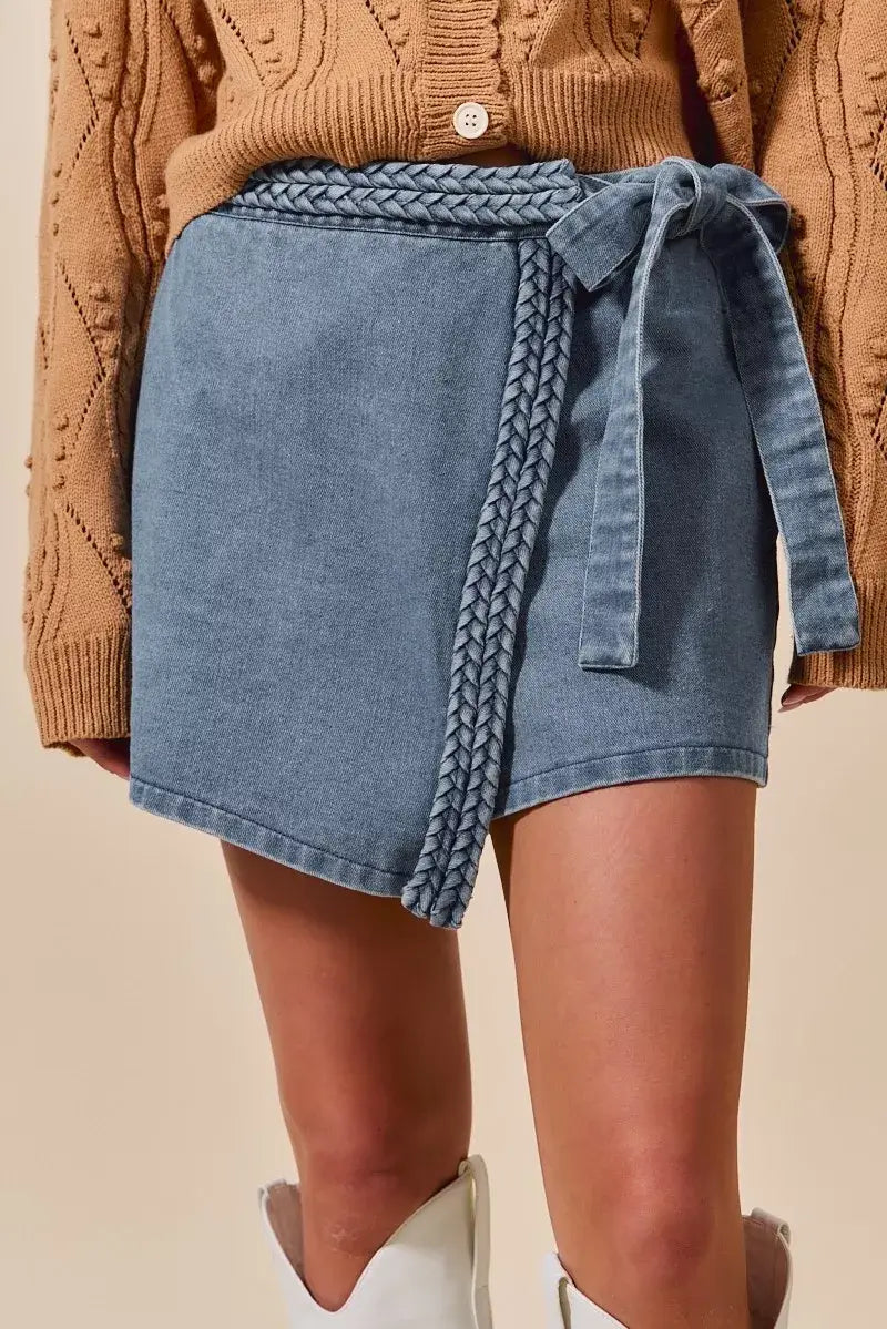 Trendy women’s wrap skort featuring braided trim in blue denim, styled with a cozy sweater.