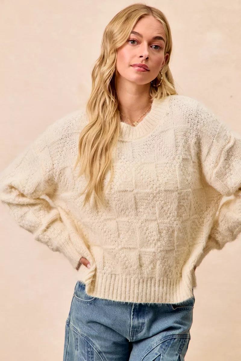 BiBi Checker Board Drop Shoulder Sweater worn by a model, featuring a cozy cream color and relaxed fit.