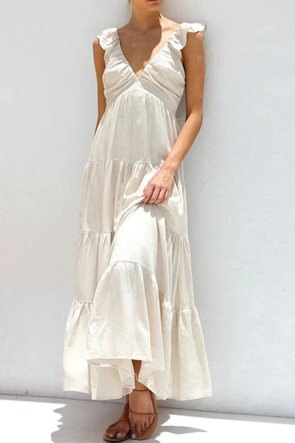 Model wearing a Ruffled V-Neck Tiered Dress in cream, showcasing the elegant smocked cotton design.