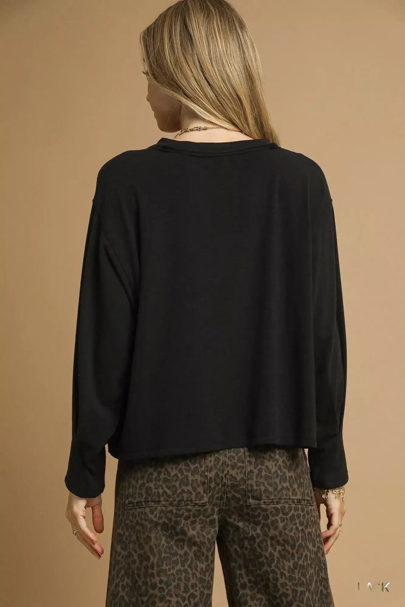 Back view of a woman wearing a black Umgee brushed fleece crewneck top with oversized fit and relaxed sleeves.