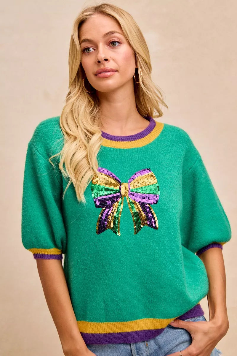 BiBi Mardi Gras Sequin Ribbon Patched Sweater featuring a colorful sequin bow design and vibrant colors for festive occasions.
